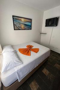 a bedroom with a bed with an orange flower on it at Pousada Mazé in Itanhaém