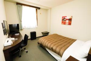a hotel room with a bed and a desk with a computer at ホテルララプラス in Nirasaki