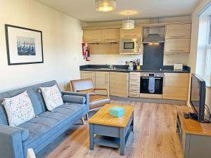 a living room with a blue couch and a kitchen at Solara Breeze in Reighton