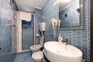 La salle de bains est pourvue de carrelage bleu, d'un lavabo et de toilettes. dans l'établissement Tiffany Apartment, à Finale Ligure 17 autres photos