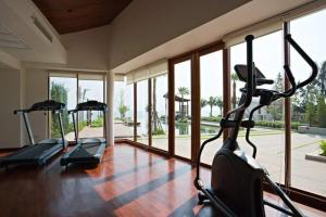 a gym with three treadmills in a room with windows at Pranaluxe Pool Villa ORG in Pran Buri