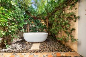 a white bath tub sitting on a pebble floor at La Ramona Charming Hotel in Tamarindo