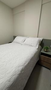Un dormitorio con una gran cama blanca y una mesita de noche. en Studio Live 2 Moderno e Aconchegante, en Uberlândia 29 fotos más