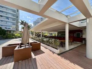 eine Terrasse mit einem Sonnenschirm, Stühlen und einem Tisch in der Unterkunft Apartamento para aluguel de temporada in Bertioga