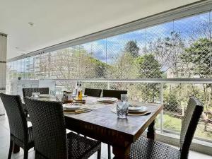 ein Esstisch mit Stühlen und ein großes Fenster in der Unterkunft Apartamento para aluguel de temporada in Bertioga