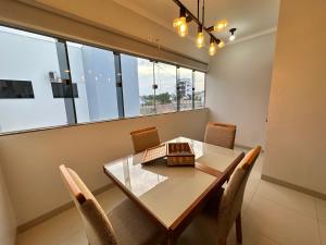a dining room with a table and chairs and windows at Apto próx Hospital Regional até 6 pessoas com garagem e wifi in Nova Mutum