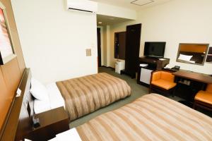 a hotel room with two beds and a desk at ホテルララプラス in Nirasaki +32 photos