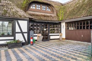 a house with a thatched roof with a tiled patio at Ferienwohnung Eichkater in Dannau