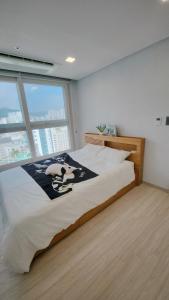 a large bed in a room with a large window at Central Height Apartment Royal in Busan