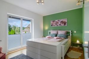 a bedroom with green walls and a bed with pink pillows at Ferienwohnung Refugium Schönenberg in Sigmaringen