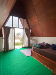 サンバラン・ラワンにあるRoman Homestay syariahの緑の床と大きな窓のある寝室
