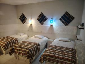 ウユニにあるCABAÑAS SAL y PIEDRAのベッド2台 壁に照明が付く部屋
