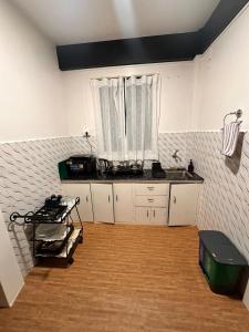 シロンにあるRoy-al Homestay 2の白いキャビネット付きのキッチン、窓が備わる客室です。