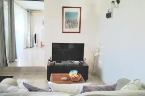 Una sala de estar con un televisor y una mesa. en Maison Mayo, en Rodney Bay Village