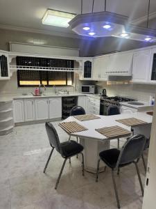 a kitchen with white cabinets and a table and chairs at Abdoun ground floor apartment in Amman