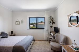 a bedroom with a bed and a desk and a window at Sobreiro22 in Lourosa