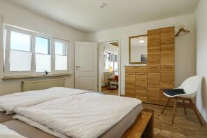 a bedroom with a large white bed and a chair at Ferienwohnung Eberle in Eriskirch