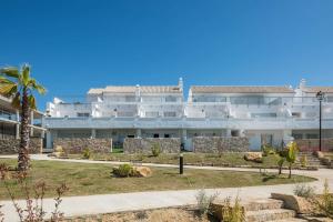 a large white building with a palm tree at Apartamento Poniente in Zahara de los Atunes