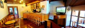 un restaurant avec un bar doté de chaises et d'une télévision dans l'établissement Hotel Sagres, à Campos do Jordão