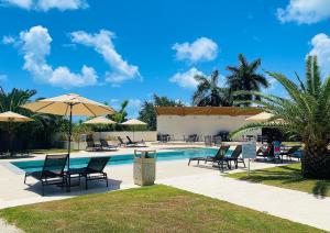 a swimming pool with chairs and umbrellas next to a pool at Maho Escape- with Pool and Gym, Lagoon view, walk to Maho Beach and Mullet Bay, walk to dinning in Maho Reef
