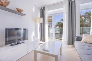 a white living room with a tv and a couch at Playa de Poniente 1-5 in Benidorm