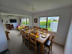 a dining room with a wooden table and chairs at Hosts on the Coast Dinah & Una's Place in Whangamata
