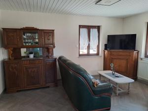 a living room with a couch and a tv at Maison Maurer in Aschbach