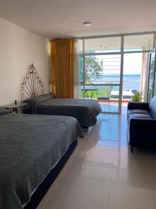 a bedroom with two beds and a couch and a balcony at Hotel Dubai de Miramar in San Blas