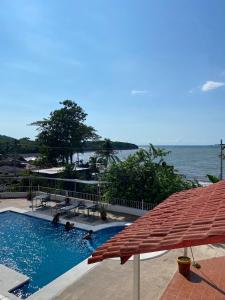 a swimming pool with an umbrella and the water at Hotel Dubai de Miramar in San Blas