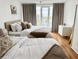 a bedroom with two beds and a couch and a window at Luxury 2-Bed 2-Bath Penthouse with Terrace in Harrow