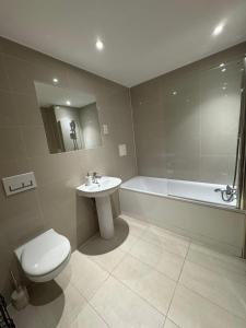a bathroom with a toilet and a sink and a tub at Luxury 2-Bed 2-Bath Penthouse with Terrace in Harrow +14 photos