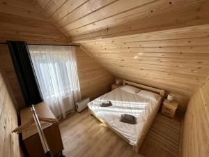 a small bedroom with a bed in a wooden room at Lemko Lodge in Novyy Kropivnik