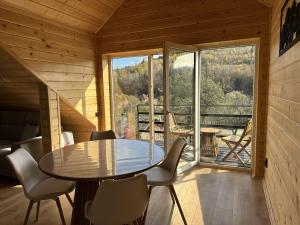 a dining room with a table and chairs and a large window at Lemko Lodge in Novyy Kropivnik
