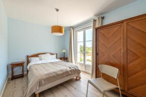 a bedroom with a bed and a chair and a window at Beach House 1km de la plage in Audierne