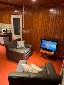 a living room with two couches and a flat screen tv at Casa Prusia, tipica de pioneros europeos in Aristóbulo del Valle