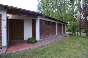 une maison en briques avec une porte marron dans une cour dans l'établissement Fun Family House - Vistalba Cuyo "Casa GEORGE", à Vistalba