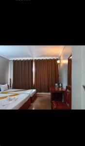 a hotel room with two beds and a desk and a window at RatanakCity hotel in Banlung