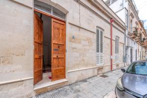 a building with wooden doors on the side of a street at San Biagio Apartment Lecce in Lecce