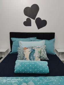 uma cama com travesseiros azuis e corações pretos na parede em Hospedagem MAR SANTO em Florianópolis