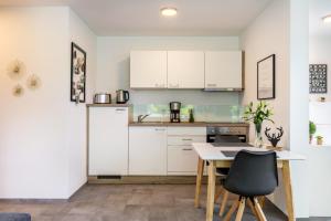 a kitchen with white cabinets and a table and chairs at Ländle Lodge bei Bregenz in Langen bei Bregenz