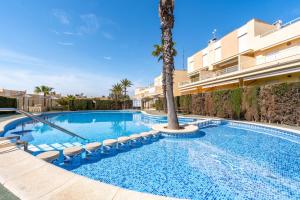 a swimming pool with a palm tree next to a building at Acag 096 in Dehesa de Campoamor