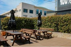 three picnic tables with umbrellas in front of a building at Bega Grand Hotel in Bega