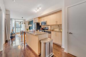 a kitchen with wooden cabinets and a counter top at Modern 2 BR Condo - By Scotiabank Arena - City View in Toronto +24 photos