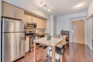a kitchen with a stainless steel refrigerator and a table at Modern 2 BR Condo - By Scotiabank Arena - City View in Toronto