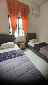two beds in a bedroom with orange curtains at Aristar D'Permatang Homestay 4 mu5lim in Bandar  Pusat Jengka