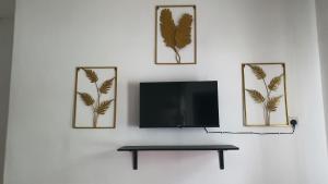 a flat screen tv on a white wall with three pictures at Aristar D'Permatang Homestay 4 mu5lim in Bandar  Pusat Jengka