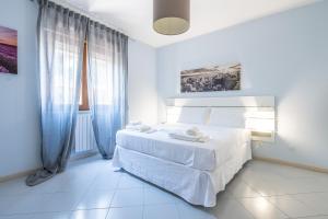 a white bedroom with a white bed with blue curtains at P012 Apartment in Cagliari