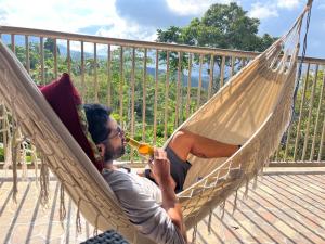 Un hombre tumbado en una hamaca bebiendo una cerveza en Finca Buenavista Sasaima, en Sasaima