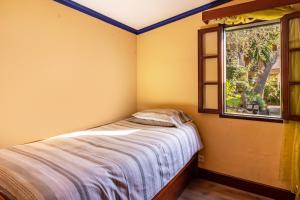 une petite chambre avec un lit et une fenêtre dans l'établissement Cayenne House, à Santa Cruz