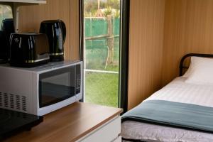 um micro-ondas sentado numa mesa ao lado de uma cama em Okuti Cottage by Tiny Away em Wairau Valley